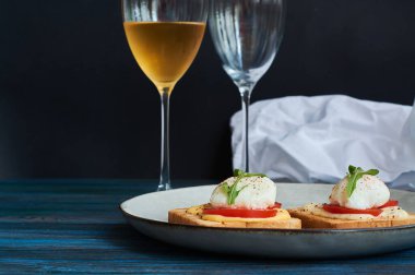 Büyük gri seramik tabak ve haşlanmış yumurta, yeşillik, domates, sos. Lezzetli bir kahvaltı. Bir kadeh şarap..