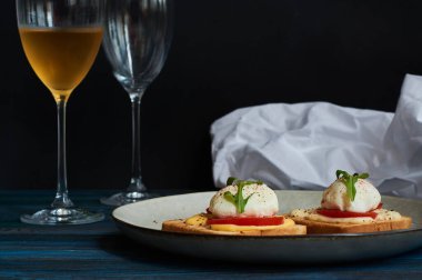 Büyük gri seramik tabak ve haşlanmış yumurta, yeşillik, domates, sos. Lezzetli bir kahvaltı. Bir kadeh şarap..