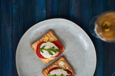 Büyük gri seramik tabak ve haşlanmış yumurta, yeşillik, domates, sos. Lezzetli bir kahvaltı. Bir kadeh şarap..