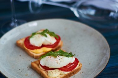 Büyük gri seramik tabak ve haşlanmış yumurta, yeşillik, domates, sos. Lezzetli bir kahvaltı. Bir kadeh şarap..