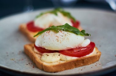 Lezzetli ev kahvaltısı dilimlenmiş taze domates ve urugula ile yumurtalı benedict..