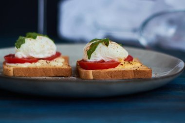 Büyük gri seramik tabak ve haşlanmış yumurta, yeşillik, domates, sos. Lezzetli bir kahvaltı. Bir kadeh şarap..