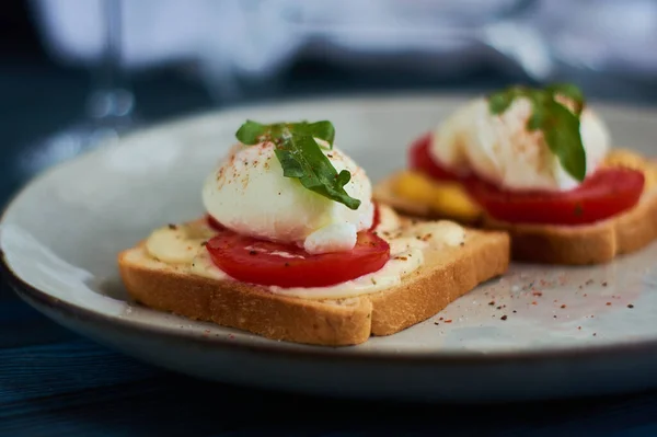 Tasty home breakfast of square toast with sliced fresh tomato and egg benedict with urugula.