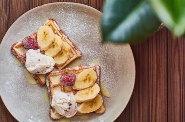 Büyük gri seramik tabak taze Belçika tatlı waffle 'ı, dondurma, çilek, muz ve konsantre süt. Lezzetli kahvaltı ve tatlı..