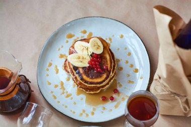 Kırmızı üzümlü taze ev yapımı krep ve gri tabakta karamel ve siyah ve koyu kahveyle el yapımı arka plan. Lezzetli kahvaltı ve hamur işleri.