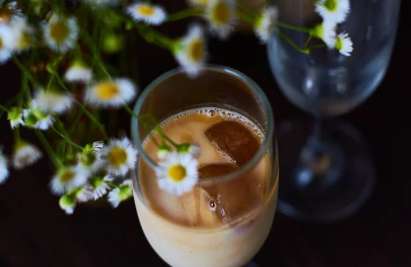 冷拿铁咖啡 咖啡加牛奶和冰块 在美丽的玻璃杯中 深色背景 小花菊花 — 图库照片