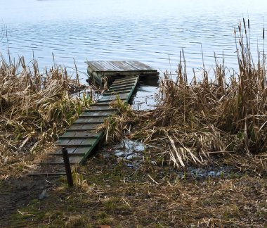 Nehir kıyısında iskele, su, rogoz ve çamur baharda
