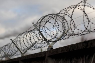 Gri gökyüzü arka plan üzerinde dikenli tel çit