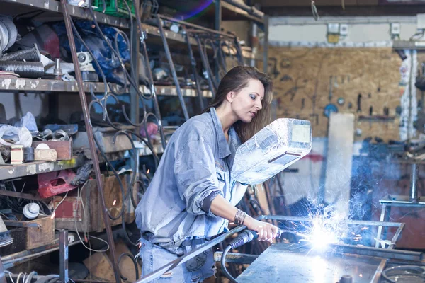 Mujer joven soldando en un taller — Foto de Stock