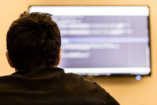 a man presenting his coding theory at big screen. background is blurry.