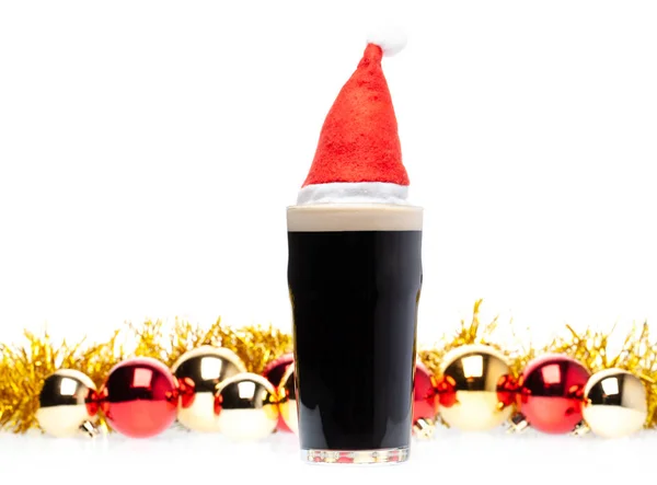 Cerveja de cerveja escura em copo de cerveja com chapéu vermelho de natal e natal — Fotografia de Stock