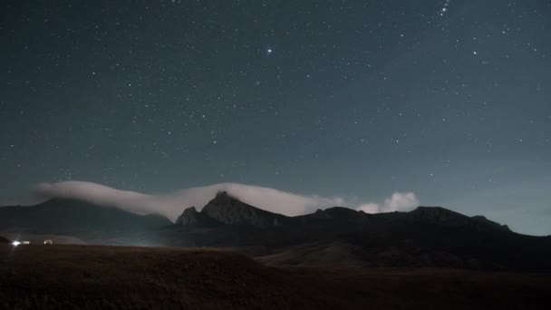 the footing of the timelapse of the night starry sky moves over the mountain range on which goes the white mist