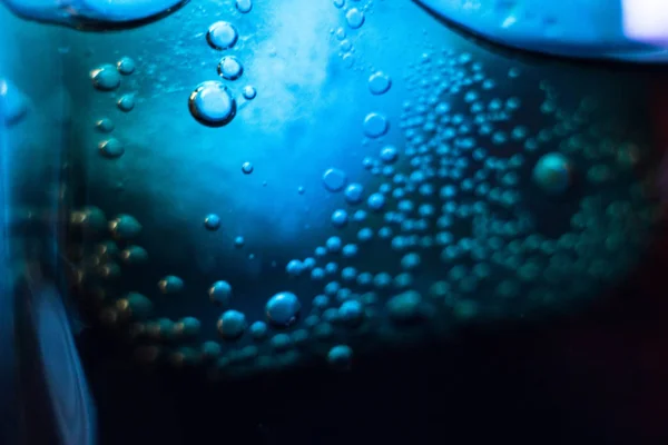 Air bubbles on a piece of ice in a soda liquid. Soda, water, bubbles, ice, texture, glass, glass, curve,