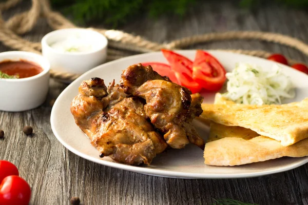 Chicken kebab on a plate with tomatoes, onions and bread