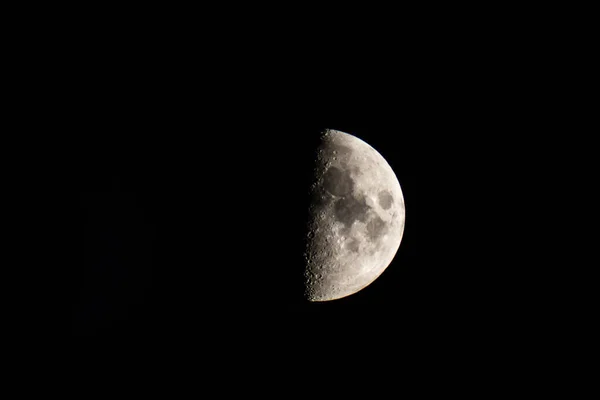 Half-lit moon against the black night sky