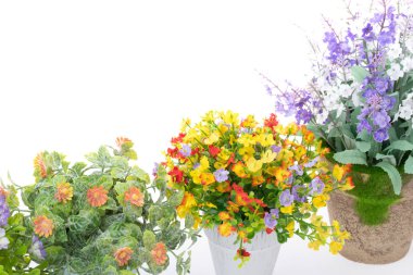 Kumaş ve plastik dekorasyon için yapılan beyaz arka plan üzerinde renkli sahte çiçek satırları.