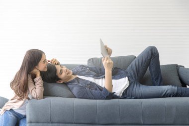 Asyalı çiftler koltukta iyi bak. Ekran üzerinden bir şeye bakıyorum. Onun tableti lüks oda. mutlulukla gülümse