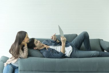 Asyalı çiftler koltukta iyi bak. Ekran üzerinden bir şeye bakıyorum. Onun tableti lüks oda. mutlulukla gülümse