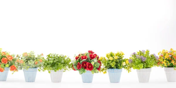 Rows of colorful fake flowers on white background, made from cloth and plastic for decoration.