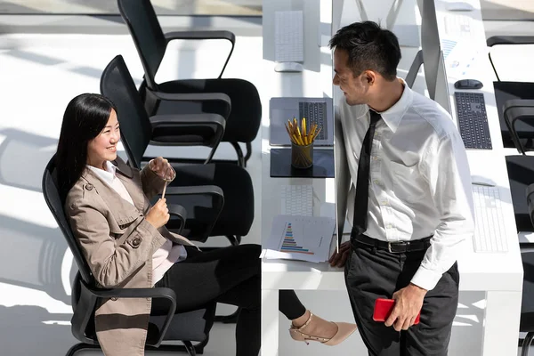 Two Asian businessmen, man and woman taking with happiness in modern office. One people stading and one sitting. Concept for being friend company