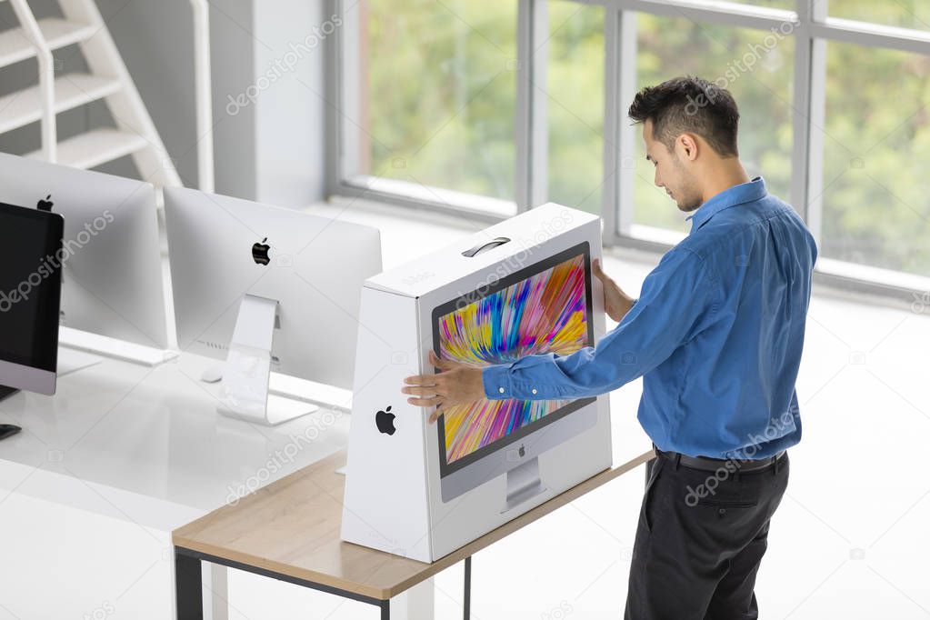BANGKOK, THAILAND - MAY 05, 2018: Asian young  businessman unbox and set up new iMac computers in office. Apple computer in one of most popular equipment for business use.