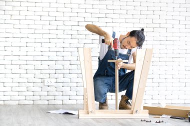 Tamirci, ahşap masa ekipmanları ile montaj olarak çalışan genç adam, bir beyaz tuğla blok için eve DIY ve kendini service.in ofis orada kavramdır.