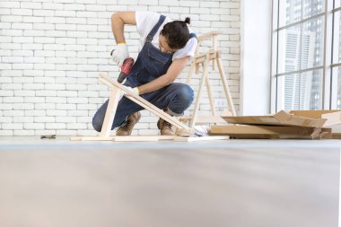 Tamirci, ahşap masa ekipmanları ile montaj olarak çalışan genç adam, bir beyaz tuğla blok için eve DIY ve kendini service.in ofis orada kavramdır.