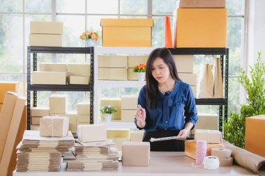 Birkaç kutu arasında duran ve kontrol genç ve güzel Asyalı kadın ev ofisinde çalışan paketler. İçin ana üs iş ve başlangıç mülkiyet kavramı.