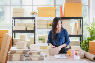 Birkaç kutu arasında duran ve kontrol genç ve güzel Asyalı kadın ev ofisinde çalışan paketler. İçin ana üs iş ve başlangıç mülkiyet kavramı.