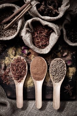 Renkli çeşitli baharatlar ve otlar doğal doku tahta kaşık ahşap plaka yandı.