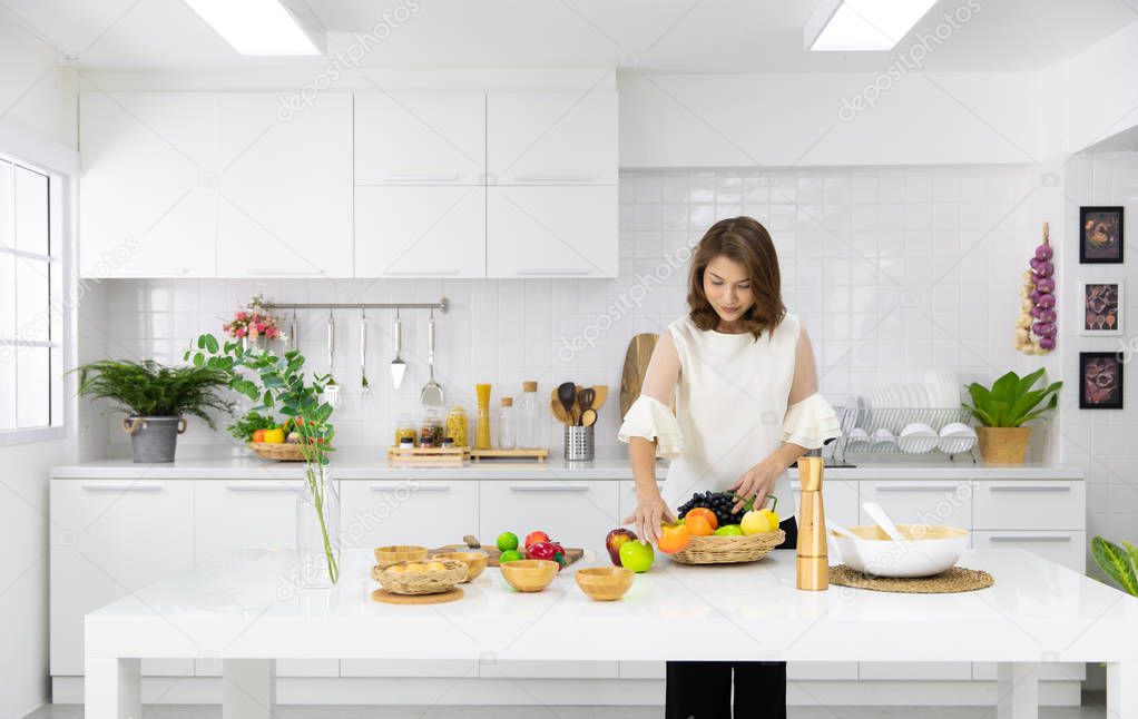 Beautiful Asian woman showing her new kitchen decoration and play with fake fruits and vegetables. Concept to modern housewife.