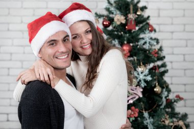 Genç ve yakışıklı beyaz adam ve güzel kadın ayakta ve sarılmak hugh önünde süslenen Noel ağacı. Kavram fo iyi zaman ve Noel Festivali anlarda sevgi paylaşımı.