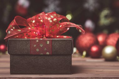 Noel süsler yakın kadar arka plan bulanık kırmızı kurdele ile bir altın kahverengi hediye kutusu.