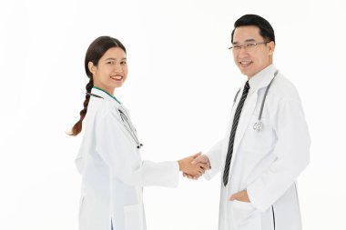 İki Asyalı Doktor aşınma omuz üzerinde üniforma stetoskop el sıkışma, beyaz arka planda izole sağlık hizmeti çalışması yapmak.