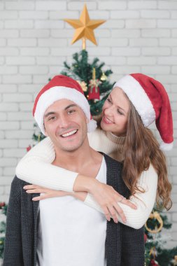 Genç ve yakışıklı beyaz adam ve güzel kadın ayakta ve sarılmak hugh önünde süslenen Noel ağacı. Kavram fo iyi zaman ve Noel Festivali anlarda sevgi paylaşımı.