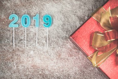 Bir çarpıcı kırmızı hediye kutusu altın şerit, Çamın dalları ve kırmızı holly Karpuzu sınır. Ahşap tahta ve bulanık mantık kar tanesi yıl 2019 mavi renk de dahil olmak üzere kopya alanı alt sol.