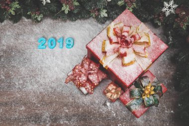 Yıl 2019 mavi renk kaplaması ahşap tahta üzerinde kar her yerinde, kopya alanı alt sol kenarındaki kırmızı hediye kutuları var.