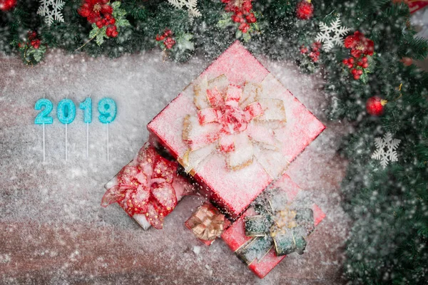 Beautiful red gift boxes bordered with pine branches red ornaments, 2019 number in middle, copy space bottom left. Snow flake fall all over.