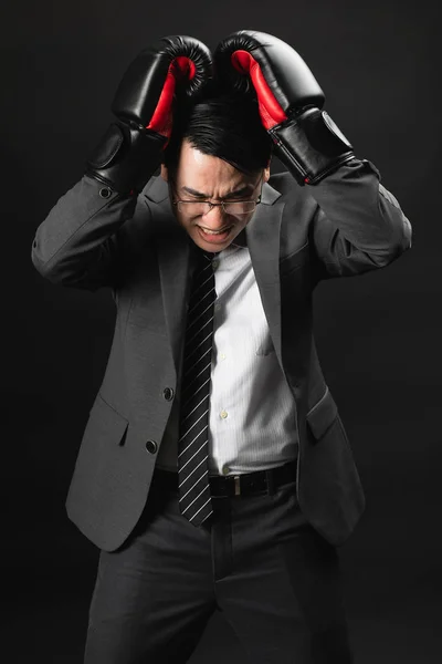Asian business man in suit and boxing gloves, express his high stressful and unhappy, losing in competition, stress with unsuccess with achieve target.