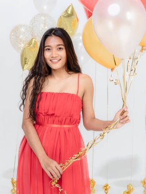 Güzel genç Asyalı kadın kırmızı elbiseli, eğlence gülümseyen mutlu parti renkli balonları tutarken. Beyaz arka plan üzerinde stüdyo portre vurdu.