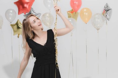 Güzel beyaz kadın siyah elbise, eğlenceli mutlu gülümseyen holding renkli balonlar parti, stüdyo çekim portre beyaz arka plan.