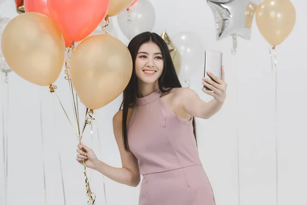 ピンクのドレス 楽しいカラフルな風船と Selfie で魅力的な若いアジア女性党 白い背景で撮影肖像画 — ストック写真