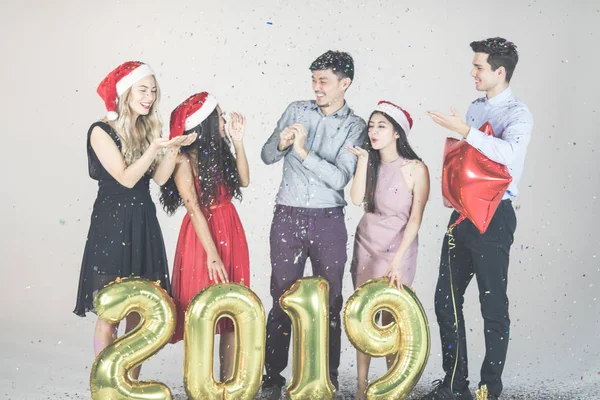 Diversity of young friends having fun together at new year\'s eve work party, holding golden ballons form of 2019 isolated on white backgroung studioshot. Picture is berry.