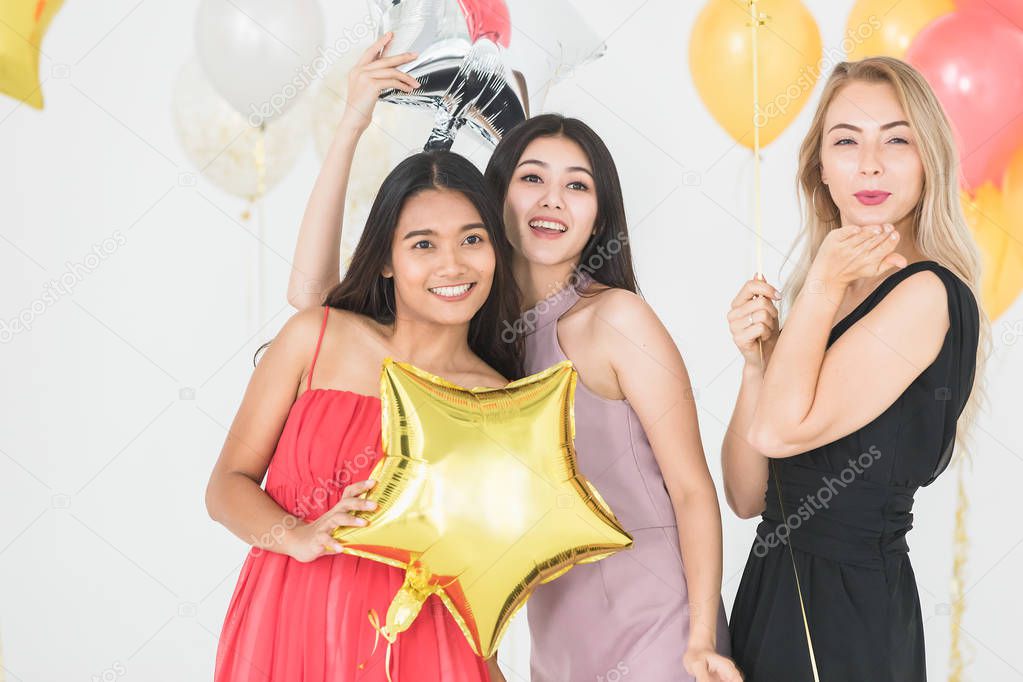 Diversity of young happy women have fun together at party, white background and colorful festive balloons.