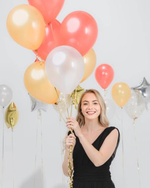 Güzel beyaz kadın siyah elbise, eğlenceli mutlu gülümseyen holding renkli balonlar parti, stüdyo çekim portre beyaz arka plan.