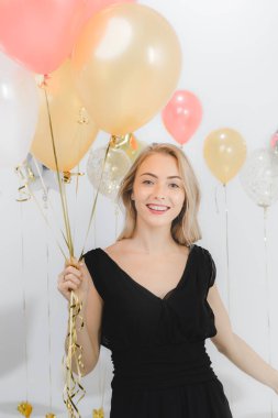 Güzel beyaz kadın siyah elbise, eğlenceli mutlu gülümseyen holding renkli balonlar parti, stüdyo çekim portre beyaz arka plan.