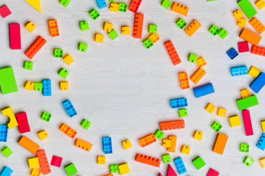 Çok renkli oyuncak blokları, ahşap tuğlalar, lego, oyun parçaları, izole beyaz ahşap zemin üzerinde çeşitli şekillerde oyuncaklar organize ediyorlar.