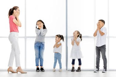 Pembe gömlek ve Asya çocuklar Asyalı kadın stand ve kendi çene tutmak, onlar büyük beyaz pencere önünde stand.