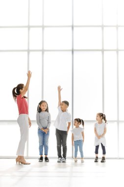 Asyalı kadın ve küçük Asya kız büyük beyaz pencerenin önünde Asyalı çocuklar arasında onların kişinin elini kaldır.