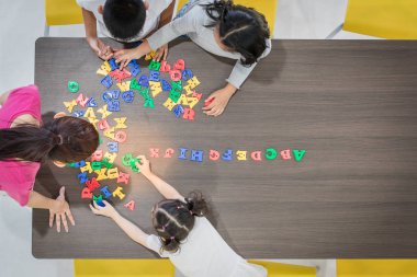Çocuklar ve öğretmenler sınıfta renkli oyuncaklar oynuyorlar. Okul boş zamanlarında mutlu ve eğlenceli öğrenme, beyin geliştirme aktiviteleri kavramı.
